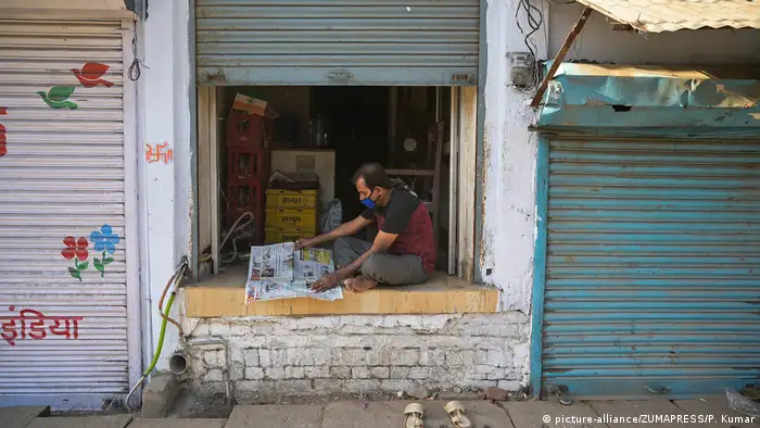 A shopkeeper reads the newspaper at his shop during lockdown in wake of Coronavirus pandemic in Prayagraj, Uttar Pradesh, India