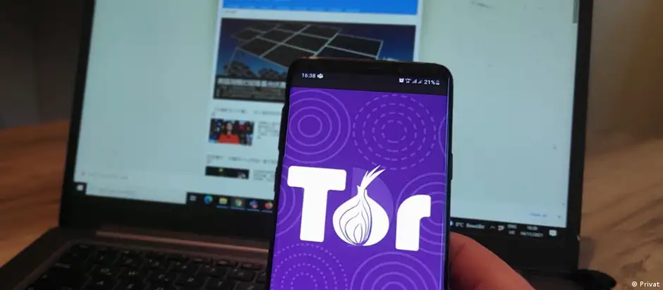 A cell phone screen showing the Tor logo in front of a laptop displaying DW's website